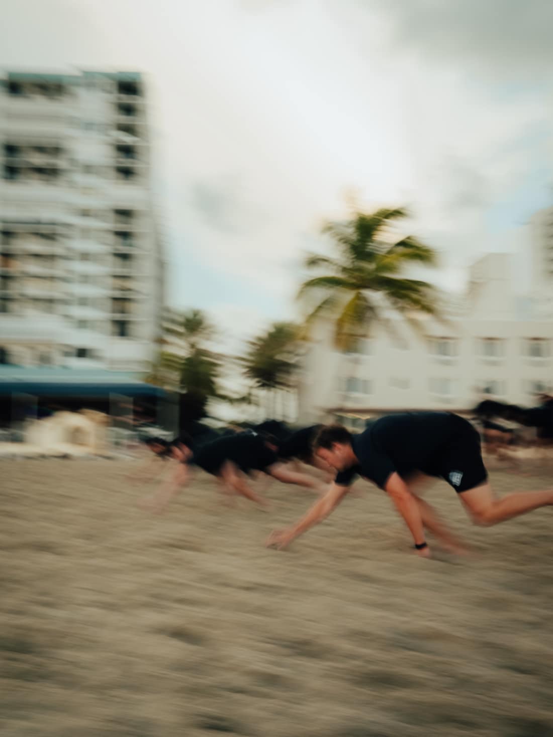 A group crawling across the sand during a THRVE beach workout
